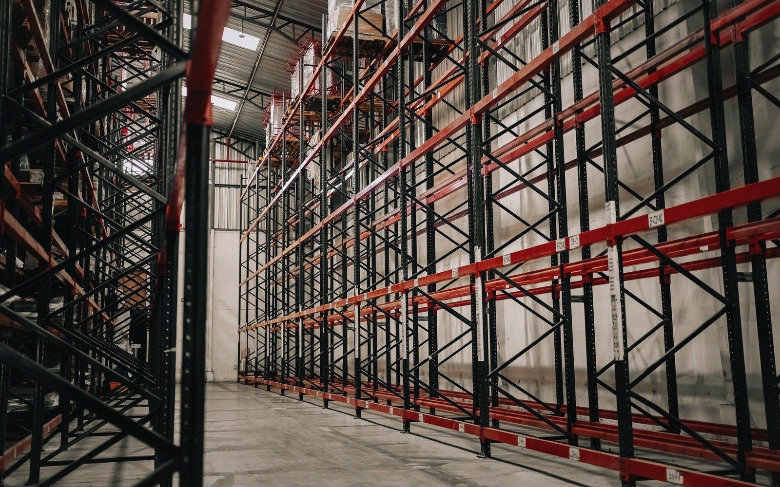 Empty pallet racking shelves stretch down a warehouse aisle