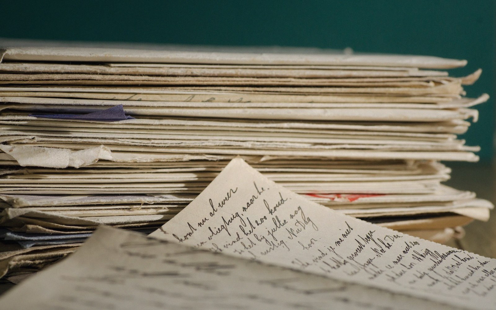 A stack of aged handwritten letters with one page unfolded showing cursive script