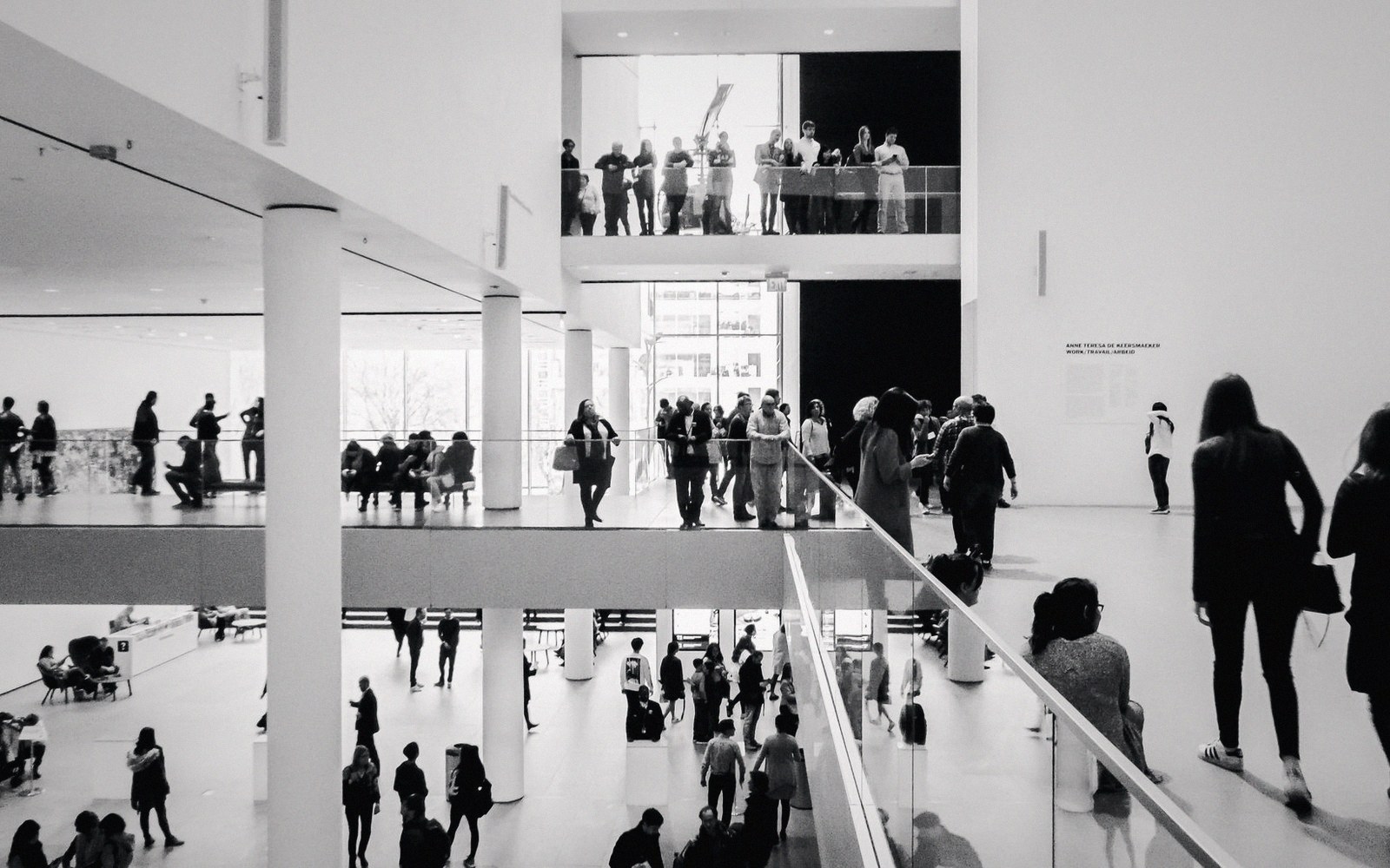 Visitors move across multiple levels of a museum's open, white atrium